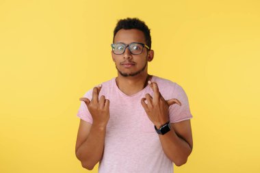 Kafası karışmış Afro-Amerikan genci sarı arka planda umut içinde parmaklarını uzatıyor.