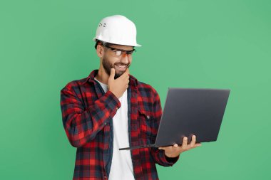 Yeşil arka planda bilgisayarı olan sakallı yakışıklı bir mühendis ya da sıradan giyimli bir müteahhit. Düşünen adam.
