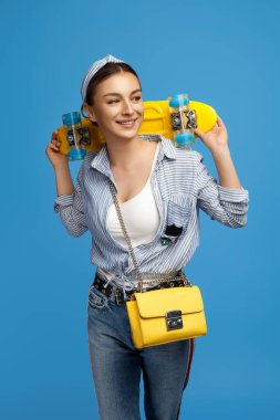 Sarı kuruşlu ya da kaykaylı zarif genç bir kadın mavi arka planda poz veriyor..