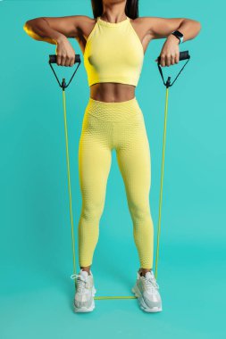 Mavi arka planda bantlı omuzlarını esneten genç bir kadının yakın plan fotoğrafı..