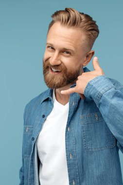 Neşeli sakallı hippi sarışın genç adam mavi arka planda telefon sinyali göster.