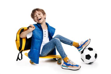 Sarı kaykaylı beyaz arka planda oturan sevimli, gülen sarışın çocuk. Okula Dönüş