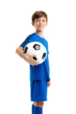 Beyaz arka planda klasik futbol topuyla poz veren mavi spor kıyafetli kendinden emin bir gencin portresi..