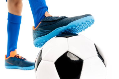 Yakın plan görüntü, genç futbolcu, mavi spor kıyafetli beyaz arka planda klasik futbol topunun bacağını tutuyor..