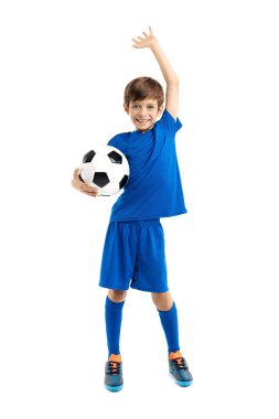 Mavi spor kıyafetli, elinde klasik futbol topu olan gülümseyen genç çocuk, beyaz arka planda kazanmayı kutluyor..