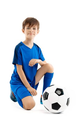 Mavi spor kıyafetli çekici bir genç beyaz arka planda klasik futbol topuyla poz veriyor..