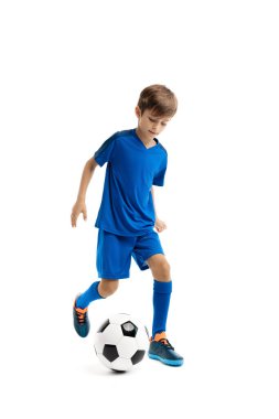 Mavi spor kıyafetli çalışkan genç beyaz arka planda klasik futbol topuyla oynuyor..