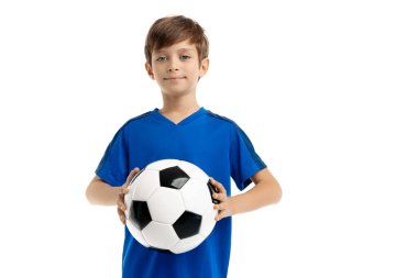 Beyaz arka planda klasik futbol topuyla poz veren mavi spor kıyafetli kendinden emin bir gencin portresi..