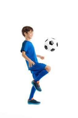 Beyazlar üzerinde klasik futbol topuyla mavi spor egzersizleri yapan motive olmuş genç bir çocuk. Spor ve motivasyon.