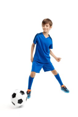 Mavi spor kıyafetli çalışkan genç beyaz arka planda klasik futbol topuyla oynuyor..