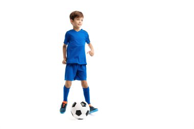 Mavi spor kıyafetli genç, beyaz arka planda klasik futbol topuyla oynuyor..