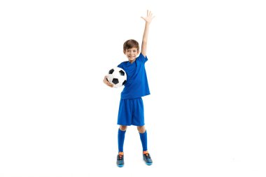 Mavi spor kıyafetli neşeli çocuk elinde klasik futbol topu, kazananı kutla.