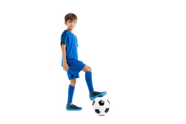 Sevimli genç futbolcu, mavi spor kıyafetli klasik futbol topunun bacağını tutuyor..