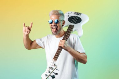 Yakışıklı hippi, neon ışıklarla beyaz bas gitar çalıyor. Rock müzik konsepti. Kaya hareketi.