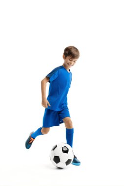 Mavi spor kıyafetli genç, beyaz arka planda klasik futbol topuyla oynuyor..