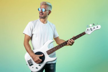 Sarı saçlı modern hippi adam renkli arka planda sanal gerçeklik gözlüğü takıyor..