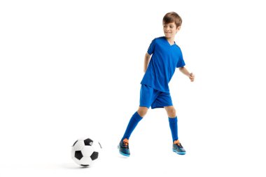 Mavi spor kıyafetli enerjik genç beyaz arka planda klasik futbol topuyla oynuyor..