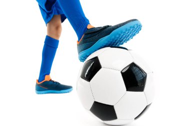 Yakın plan görüntü, genç futbolcu, mavi spor kıyafetli klasik futbol topunun bacağını tutuyor..