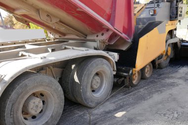 İnşaat sırasında çakıl tabanına taze asfalt ya da bitumen yerleştiren bir asfalt makinesi.