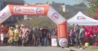 Suwanee, GA / USA - October 15, 2022:  People wearing Halloween costumes begin walking and running at the start line of a fall festival 5K race on October 15, 2022 in Suwanee, GA.