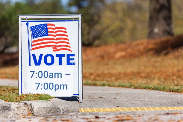 A roadside sign at a voting precinct gives the hours that people can vote.