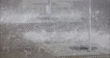 Closeup of water splashing onto concrete in public park fountain. 