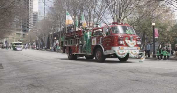 2023年3月11日アトランタ 緑とオレンジのバナーとストリーマーで装飾されたヴィンテージの赤い消防車が 毎年3月11日にアトランタで開催されるセント パーク パレードの一環としてピーチツリー ストリートを移動します — ストック動画