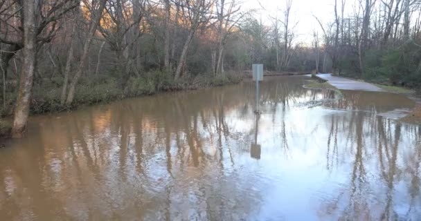広いショットは ジョージア州のレクリエーション緑地で看板や歩道を追い越した小川からの洪水の水を示しています — ストック動画