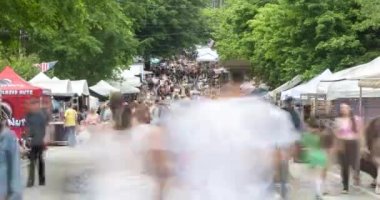 Atlanta, GA / ABD 29 Nisan 2023: Timelapse, 29 Nisan 2023 tarihinde Atlanta, GA 'da düzenlenen Inman Park Festivali' nde satıcı çadırları hakkında hareket eden büyük bir kalabalığın hareket bulanıklığını gösteriyor.. 