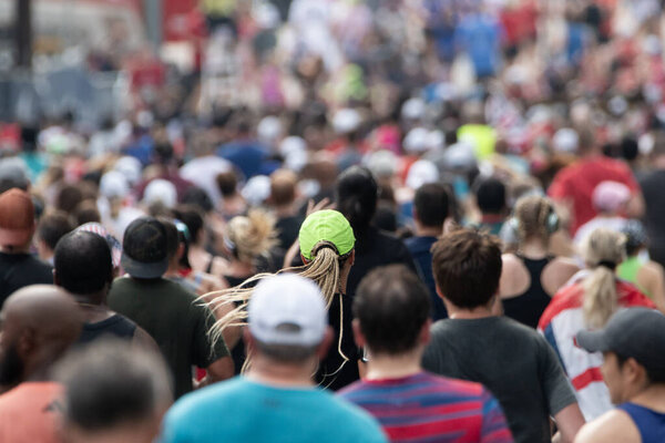 Atlanta, GA / USA - July 4, 2023:  A lone green neon hat stands out in a massive crowd of runners finishing the Peachtree Road Race on July 4, 2023 in Atlanta, GA. 