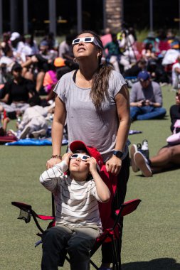 Atlanta, GA / USA - 8 Nisan 2024: Anne ve oğlu, 8 Nisan 2024 tarihinde Atlanta, GA 'da düzenlenen bir saat partisinde toplam güneş tutulmasını izlemek için özel gözlüklerle bakıyorlar.