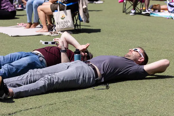 2024年4月8日 美国亚特兰大 2024年4月8日 两名男子躺在地上 透过特别的眼镜观看在美国亚特兰大举行的一个观看日全食的聚会 免版税图库照片