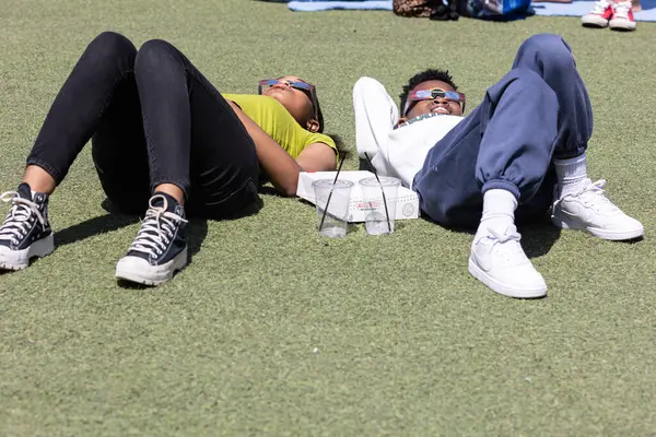 2024年4月8日 美国亚特兰大 2024年4月8日 两名青少年躺在地上 透过特别的眼镜观看日全食 图库图片