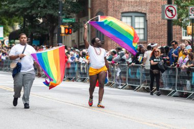 Atlanta, GA / USA - October 15, 2023:  Two men wave pride flags while walking in the annual pride parade on October 15, 2023 in Atlanta, GA. clipart