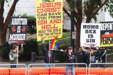 Atlanta, GA / USA - October 15, 2023:  A woman defiantly waves pride flags directly in front of anti-gay activists holding homophobic signs on October 15, 2023 in Atlanta, GA. clipart