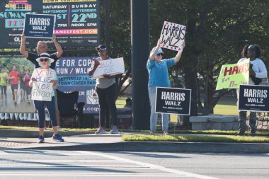 Suwanee, GA / USA - September 7, 2024:  Democratic party activists encourage vehicles to blow their horns as they hold up signs at a Honk for Kamala Harris campaign event, on September 7, 2024 in Suwanee, GA. clipart