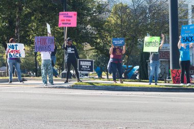 Suwanee, GA / USA - September 7, 2024:  Democratic party volunteers encourage passing vehicles to blow their horns as they hold up signs at a Honk for Kamala Harris campaign event, on September 7, 2024 in Suwanee, GA. clipart