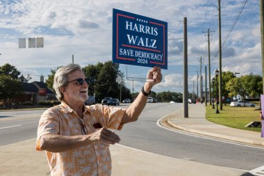Lawrenceville, GA / USA - 5 Eylül 2024: Kamala Harris 'in 5 Eylül 2024' te Lawrenceville, GA 'da bulunan kalabalık bir sokak köşesinde yerel bir Honk etkinliğinde kampanyasını destekleyen bir adam coşkuyla bir tabela tutuyor..