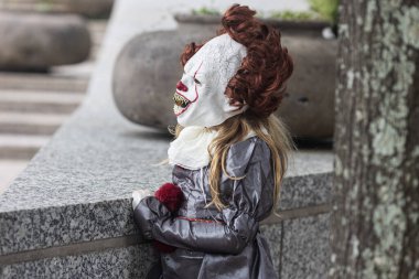 Atlanta, GA / USA - September 2, 2023:   A child wears a scary IT clown mask while waiting for the annual Dragon Con parade to begin, on September 2, 2023 in Atlanta, GA.  clipart