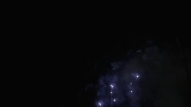 Yavaş çekim havai fişeklerin fırlatıldığını, sonra patladığını ve zifiri karanlık bir gökyüzüne doğru parladığını gösteriyor..