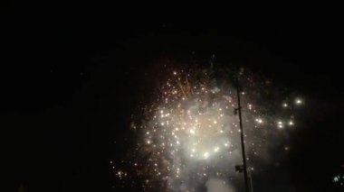 Ağır çekim, zifiri karanlık gökyüzüne karşı parıldayan ve parıldayan havai fişekleri gösteriyor..