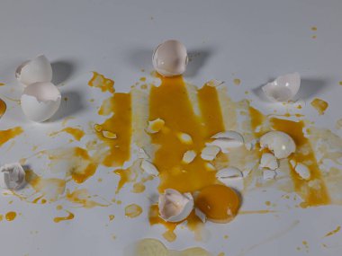 Beyaz zemin üzerinde dağınık kırık yumurtalar soyut arkaplan plakası oluşturur.