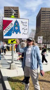 Atlanta, GA / ABD 14 Mart 2025: Dikey video 14 Mart 2025 'te Gürcistan eyaleti başkentinde 14 Mart 2025' te düzenlenen mitingde Trump karşıtı, Musk karşıtı bir tabela taşıyan bir kadın görülüyor.