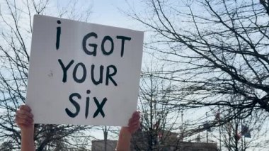 14 Mart 2025 'te Atlanta, GA' da düzenlenen Gürcistan Eyalet Kongresi 'nde düzenlenen bir mitingde, bir tarafta altı kişi, diğer tarafta ise gazilerimizi koruyoruz yazan tabelayı tutan kadınların elleri var.. 