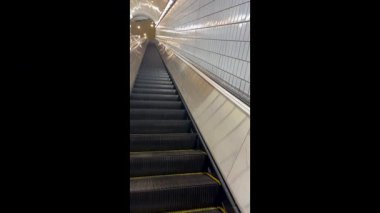 Yavaş çekim, tren istasyonu tünelinde ilerleyen çok uzun bir yürüyen merdivenin boş adımlarını gösteriyor.. 