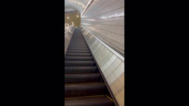 İzleme görüntüsü, çok uzun bir yürüyen merdivenin boş adımlarını gösteriyor. Tren istasyonu tünelinde yukarı doğru hareket ediyor.. 