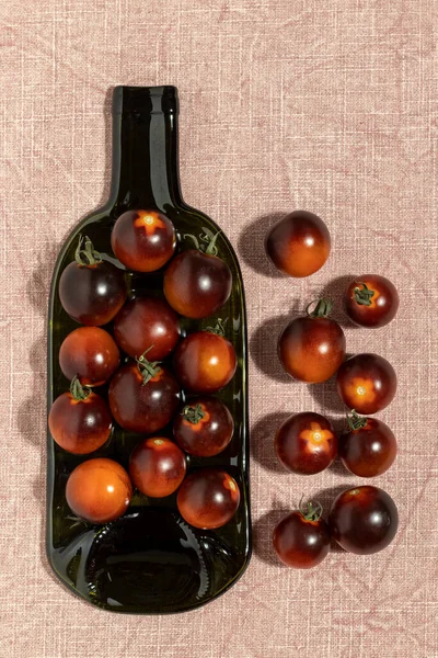Black strawberry tomatoes in a bottle plate. Top view.