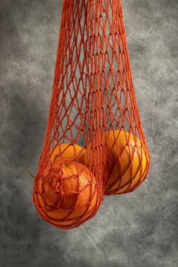 Red net shopping bag with oranges. Close up.
