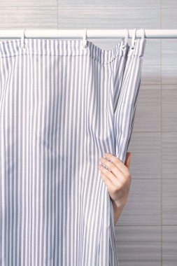 Bir kadın banyoda eli ile duş perdesini açar. Yakın plan..