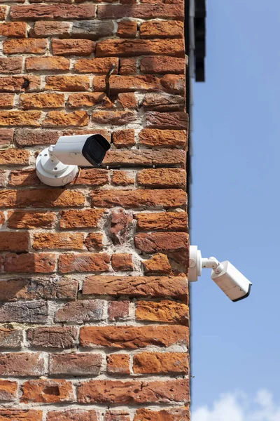 Closed-circuit television cameras on a brick wall.